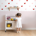 Liebevolle Kinderzimmer Deko: Rosa Herzchen Wandsticker über einem weißen Holzbett im Mädchenzimmer, harmonisches Design, handgemalter Look